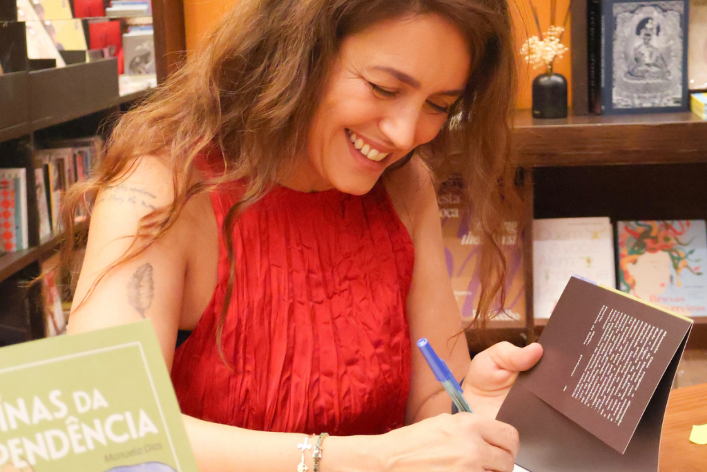 Manuela Dias escrevendo em um livro