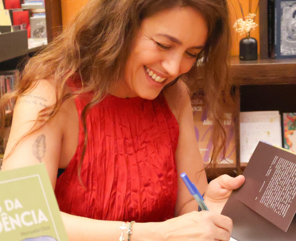 Manuela Dias escrevendo em um livro